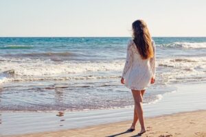 Kobieta w modnej sukience na lato chodzi po plaży